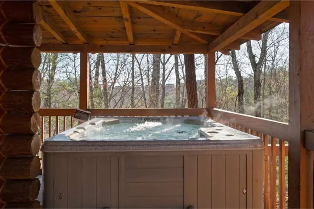 An outdoor hot tub set against a backdrop of natural surroundings and wooden structures. The area invites guests to relax and soak while enjoying tranquil views or stargazing in the evening.